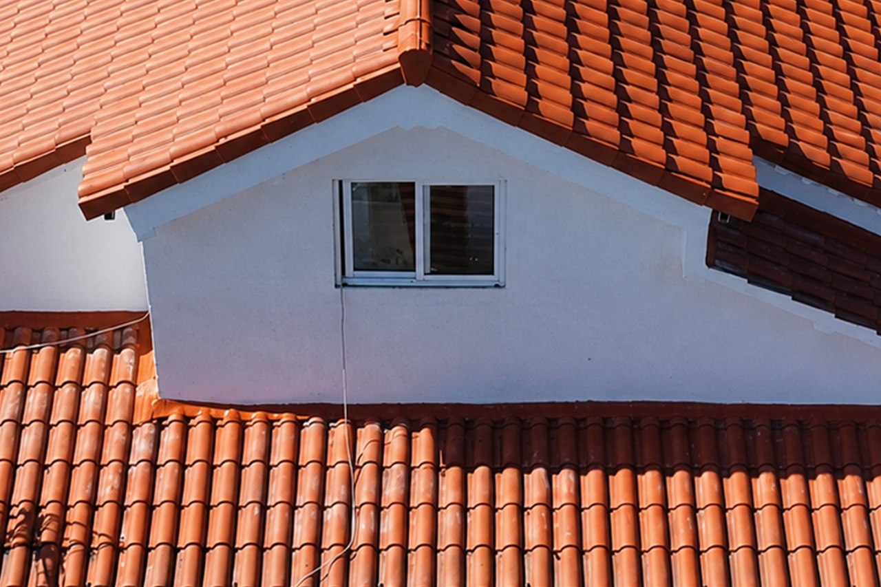 Pignon enduit blanc d'une maison, encadré par la couverture